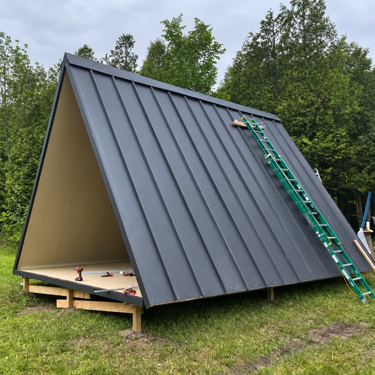 CENLUXE SIP panels being raised on site to form an A-Frame cabin roof and wall structure